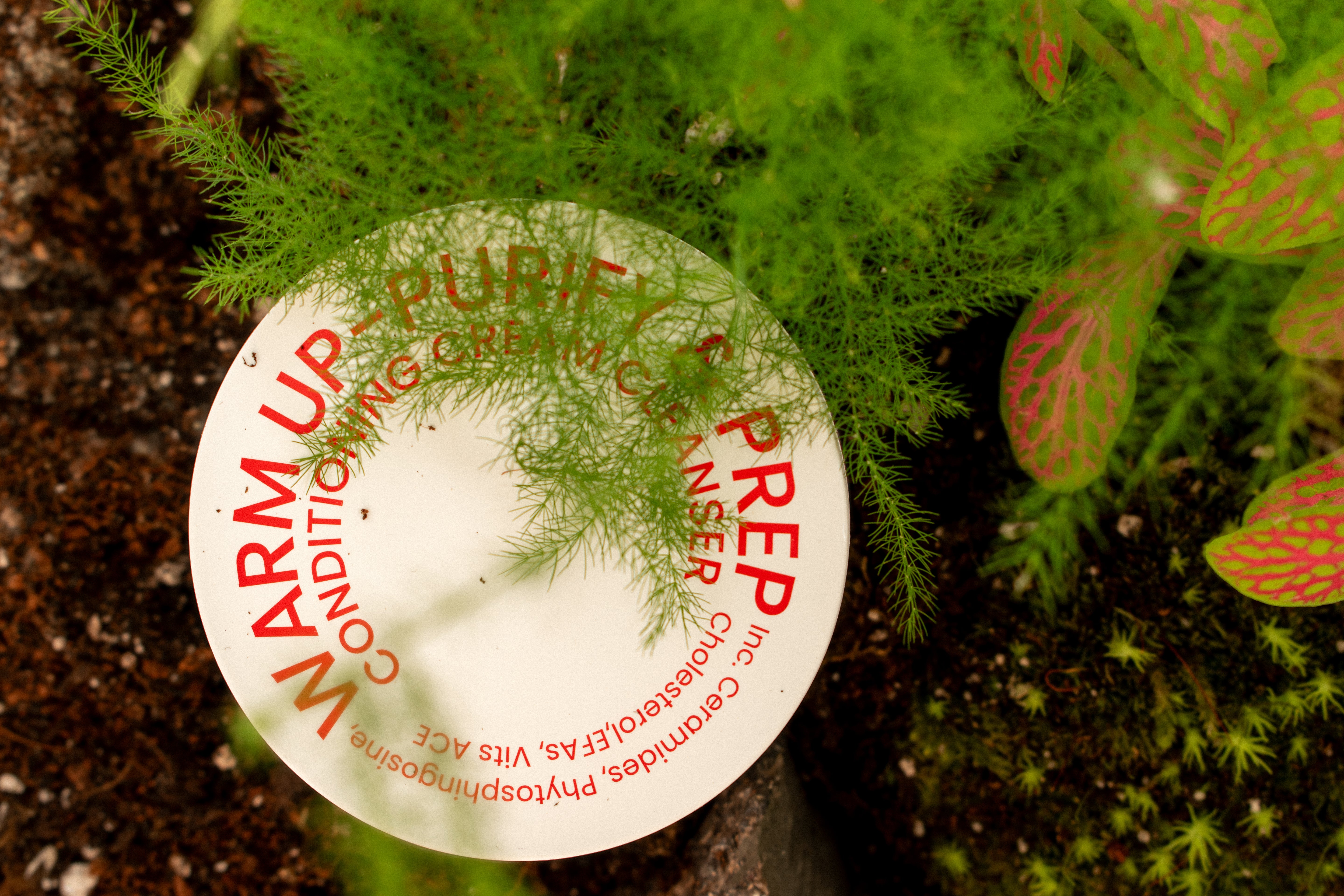 Home compostable biodegradable WARM UP skincare packaging in soil.